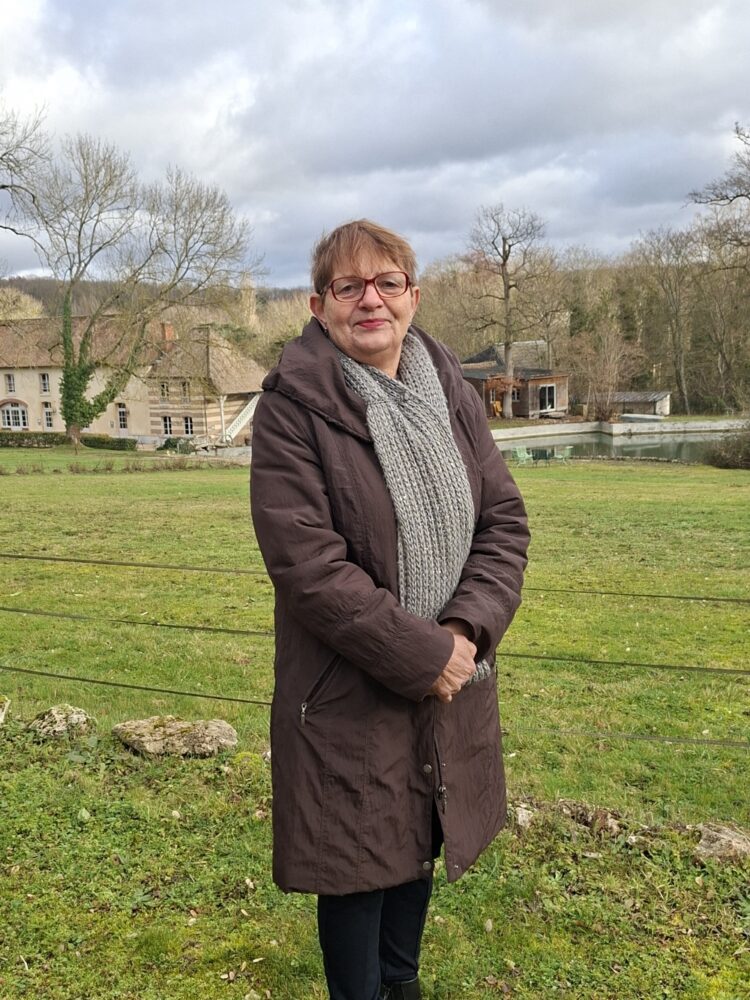 Madame DOREMUS, en fond le décor d'un beau paysage saint-aubinois, un jour de ciel clairsemé