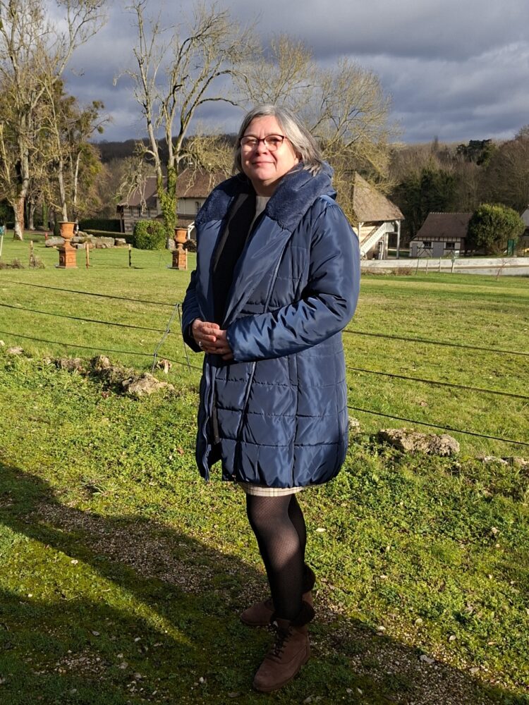 Madame DUHAMEL, en fond le décor d'un beau paysage saint-aubinois, un jour de ciel clairsemé