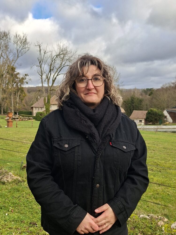 Madame LARUE, en fond le décor d'un beau paysage saint-aubinois, un jour de ciel clairsemé