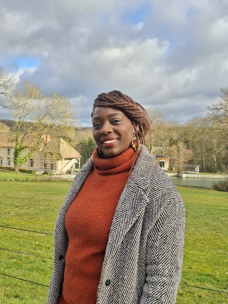 Madame MENDY, en fond le décor d'un beau paysage saint-aubinois, un jour de ciel clairsemé